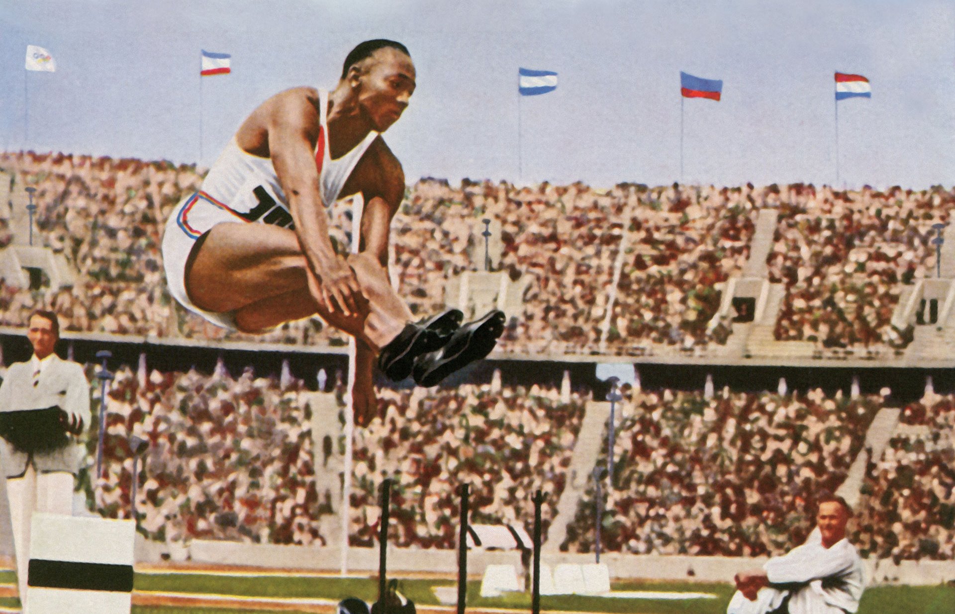 Photos Jesse Owens [États-Unis] au saut en longueur, carte postale colorisée, 1936.
