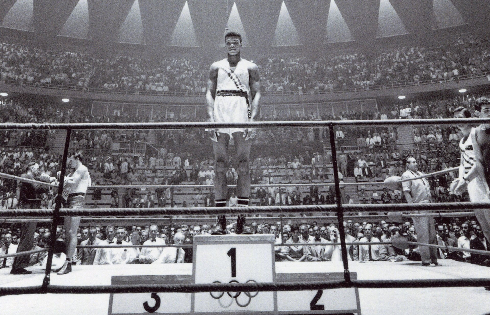 Photos Le champion des poids mi-lourds, Cassius Clay [États-Unis], sur la première marche du podium, photographie, 1960.
